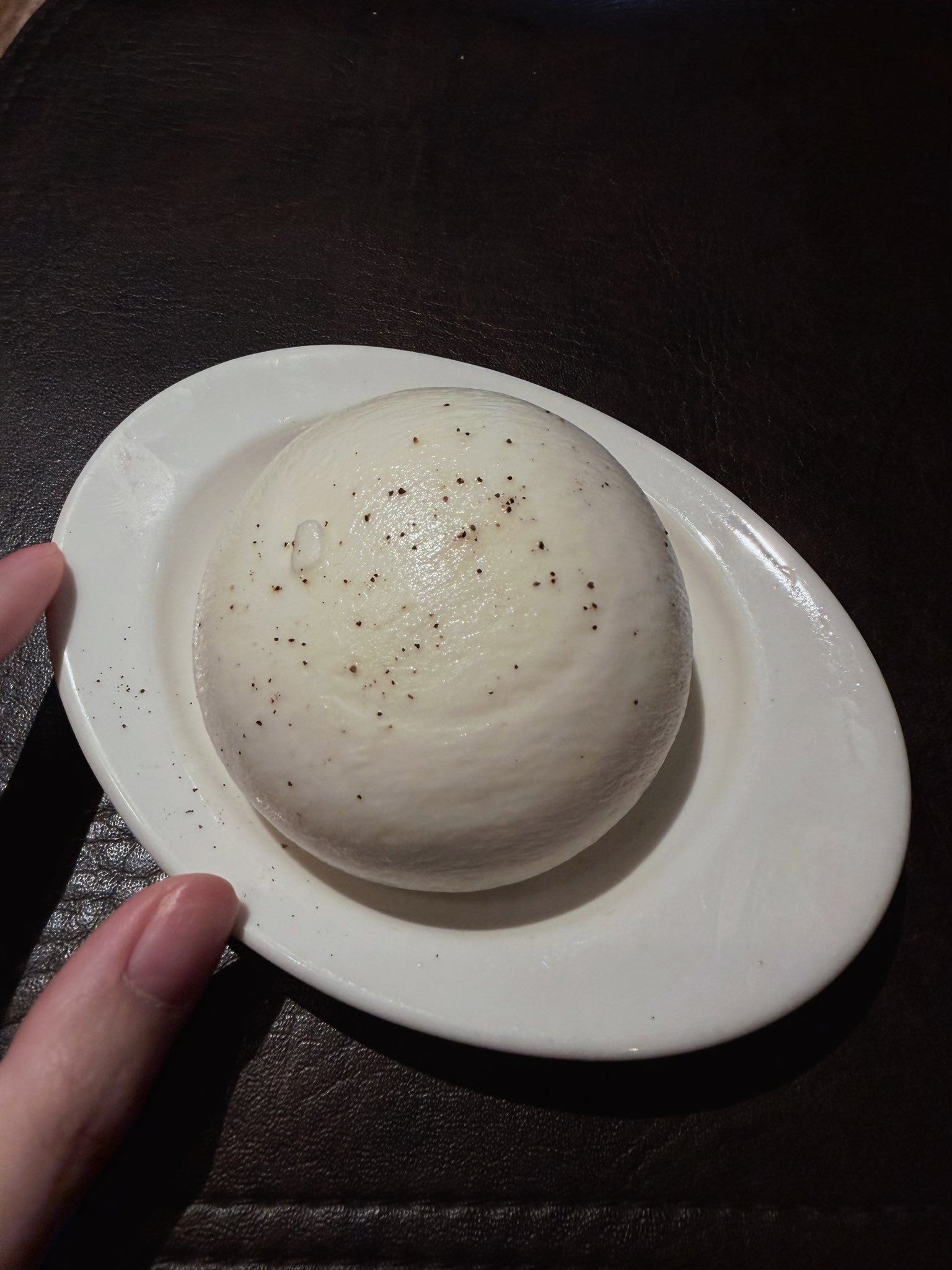A warm bread roll resting on a white side plate.